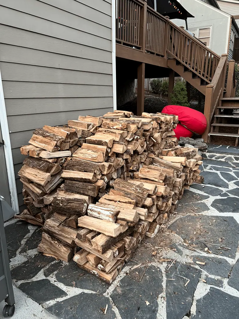 Firewood on a flagstone patio beside deck stairs